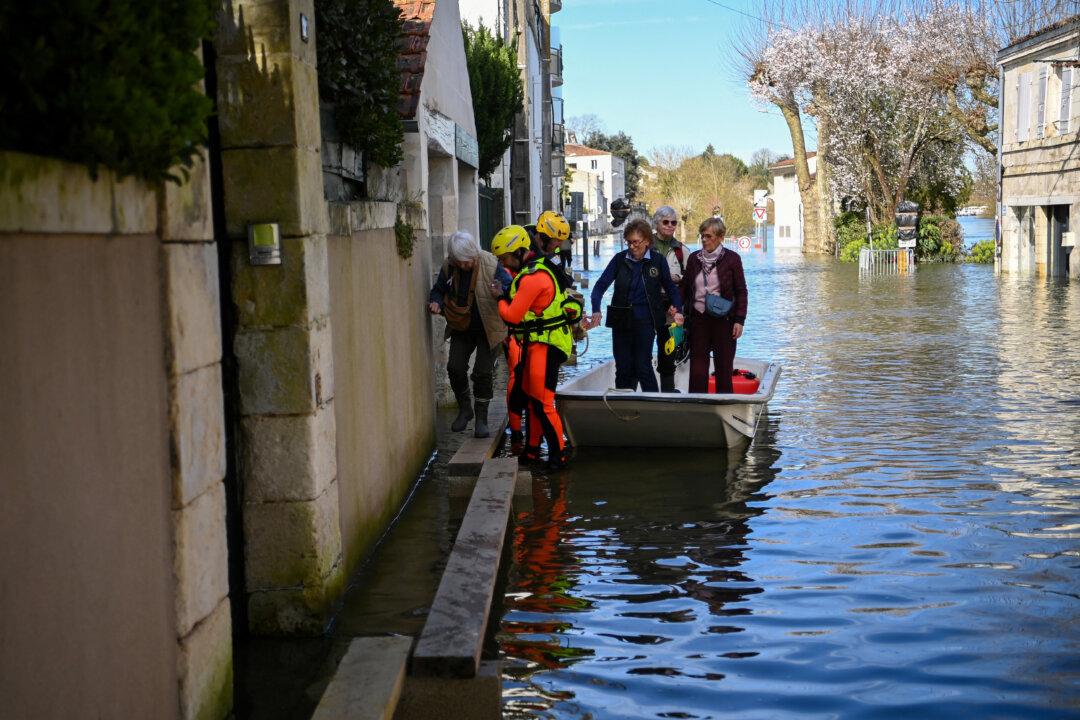 Firefighters assist elderly residents to climb from their boat as they are rescued from rising floodwaters following the passage of Storm Nils in Saintes, south-western France on February 24, 2026. The water continues to recede slowly in western France, according to Vigicrues, suggesting a gradual return to normal in some affected areas, just as the record for the longest period under red flood alert in France has been broken. (Photo by Christophe ARCHAMBAULT / AFP via Getty Images)