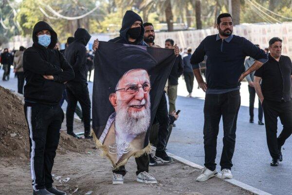 Iraqis, one holding a portrait of the assassinated Iranian supreme leader, look on as they try to approach a bridge leading to the Green Zone where the U.S. embassy is located in Baghdad on March 1, 2026. (Ahmad AL-RUBAYE / AFP via Getty Images)
