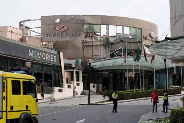 Security and civil defence workers stand outside the damaged Crown Plaza hotel, following an Iranian military strike, in Manama, Bahrain, on March 1, 2026. (Fadhel MADAN / AFP via Getty Images)