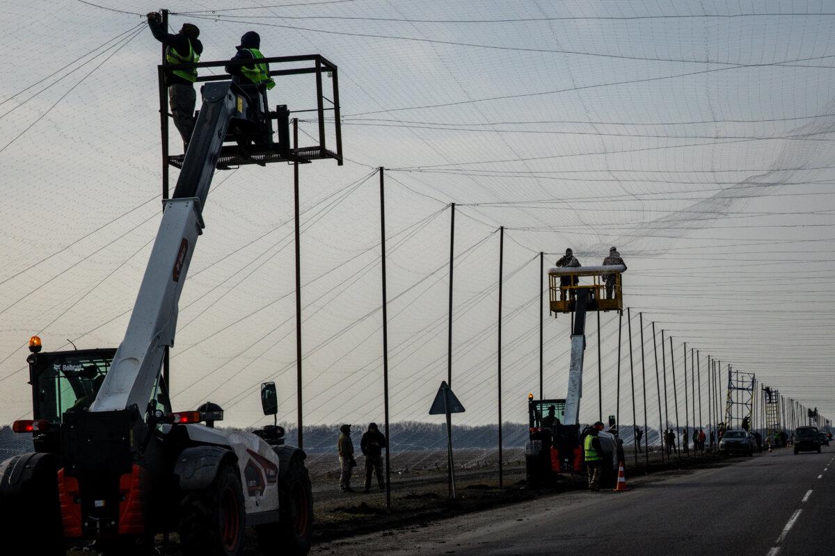 Workers install anti-drone netting on the roads in Druzhkivka, Ukraine, on March 2, 2026. (Chris McGrath/Getty Images)