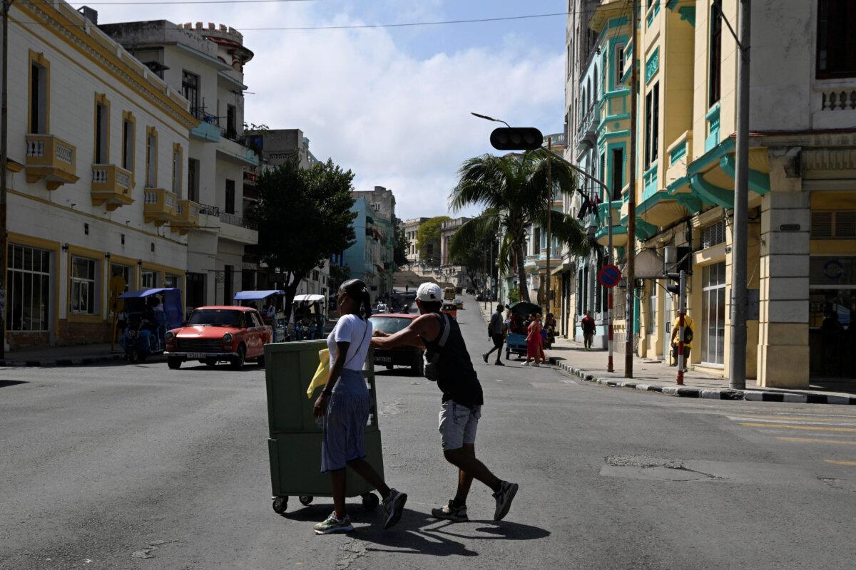 People cross an avenue as traffic lights are off during a nationwide power outage, in Havana, Cuba, on March 4, 2026. (Norlys Perez/Reuters)