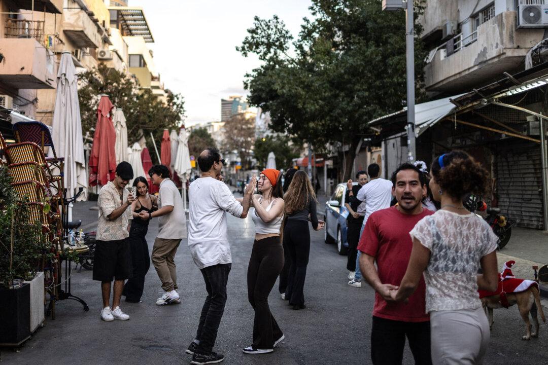 Residents dance outside a cafe along the street at Carmel market in Tel Aviv, Israel, on March 6, 2026. Israel's military on March 6 said that Iran had launched cluster bombs "multiple times" since the start of the war that began with a US-Israeli attack on the Islamic republic last week. (Olympia de Maismont / AFP via Getty Images)