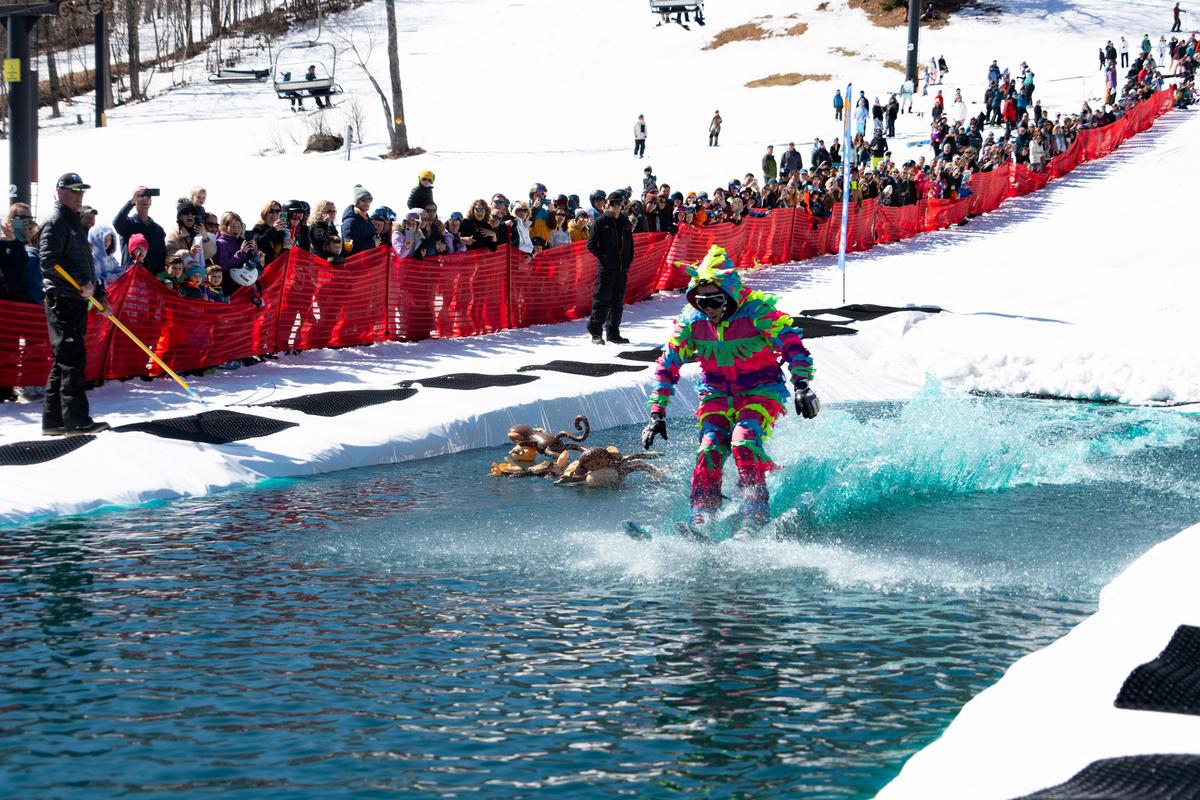 <span style="font-weight: 400;">A contestant dons a silly costume and competes in the annual Sink or Skim contest at Mount Snow, in which skiers attempt to skim across a pond on their snow skis as spirited hecklers cheer or jeer their success. (Brooke Cerbone/Vail Resorts)</span>