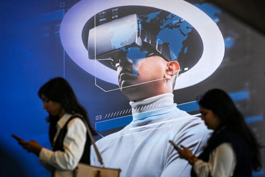 Visitors use mobile phones as they walk past a billboard advertising a virtual reality headset at the AI Impact Summit in New Delhi on Feb. 17, 2026. A 2025 Anthropic report testing 16 large language models found that all showed high-risk behavior in simulated environments. (Arun Sankar/AFP via Getty Images)