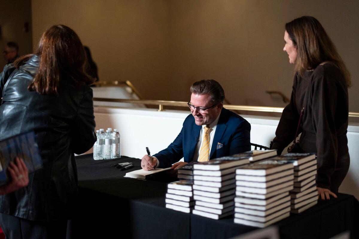 Jan Jekielek, Epoch Times senior editor and host of American Thought Leaders, signs his book, “Killed to Order,” at the Trump-Kennedy Center in Washington on March 16, 2026. (Madalina Kilroy/The Epoch Times)