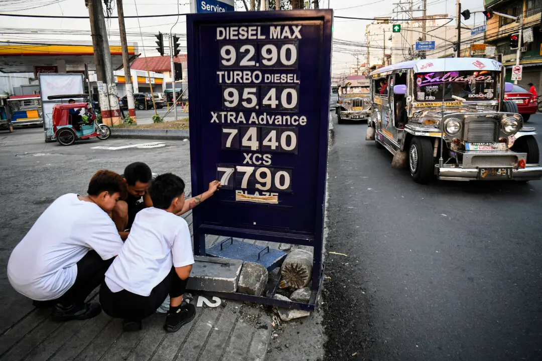 TOPSHOT - Workers change the price label of fuel at a petrol station in Manila on March 17, 2026. Oil climbed again in Asia on March 17 after prices retreated a day earlier, with investors remaining focused on the Strait of Hormuz. (Photo by Ted ALJIBE / AFP via Getty Images)