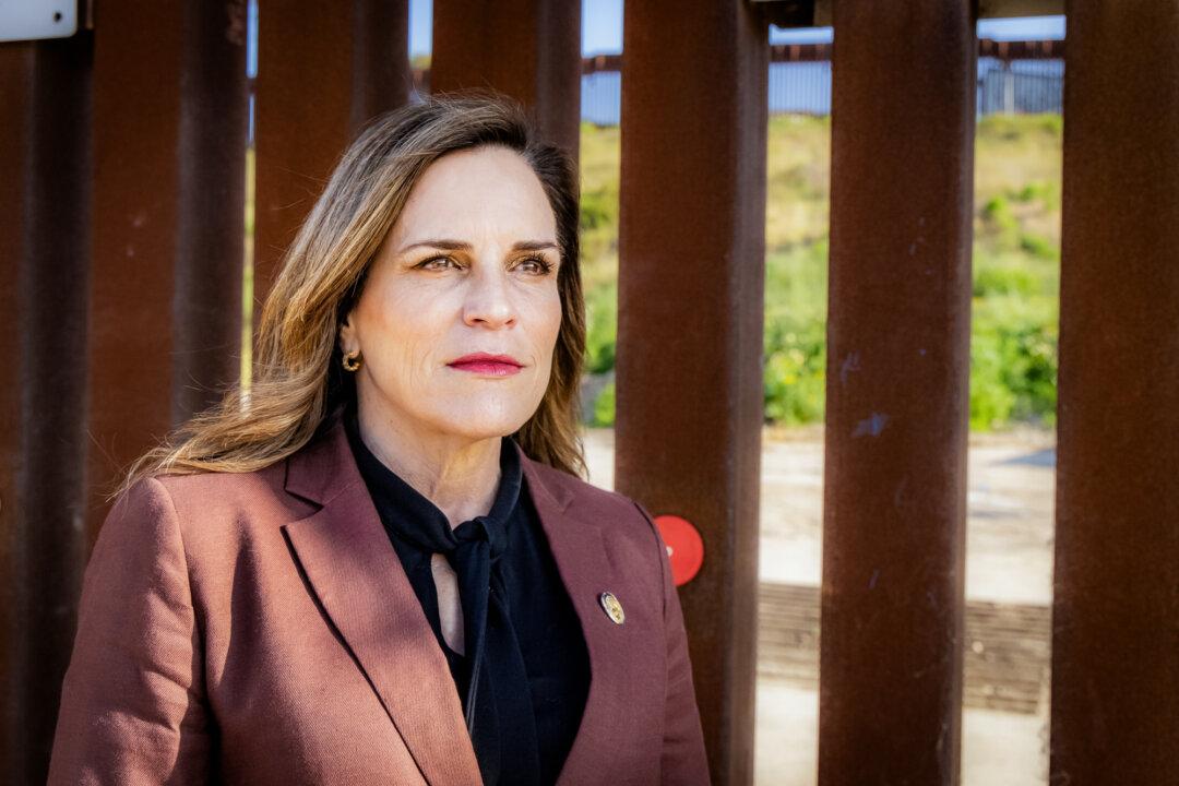 Amy Reichert, founder of Restore San Diego, stands near the U.S.–Mexico border wall in San Diego on April 11, 2024. Reichert said conditions in San Diego County have changed dramatically since Trump’s policies took effect. (John Fredricks/The Epoch Times)