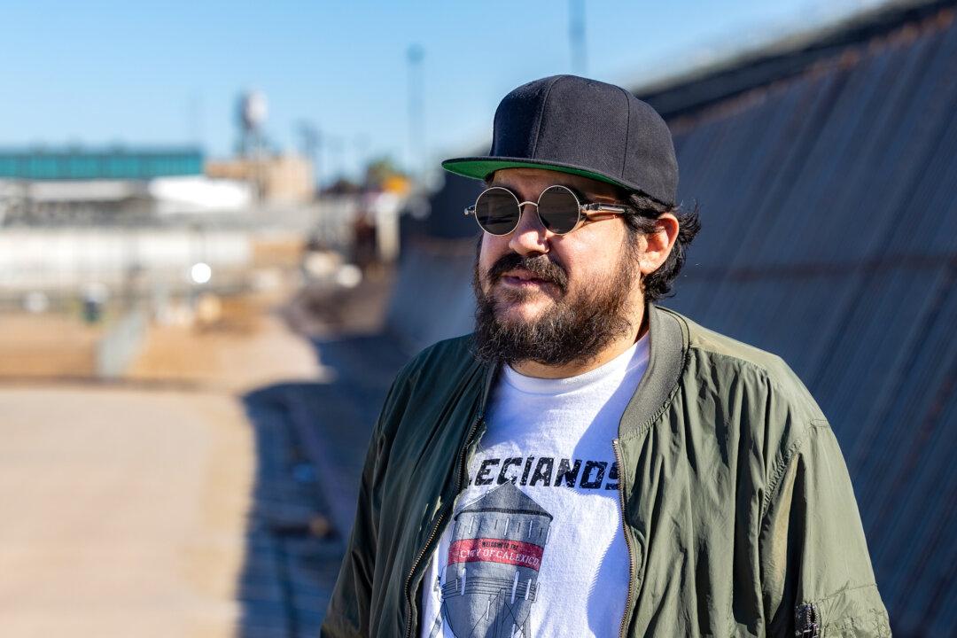 Joseph Guilin, a Calexico, Calif., resident, stands near the U.S.–Mexico border wall in El Centro, Calif., on Jan. 19, 2026. With fewer illegal border crossings in town, Guilin said tax dollars should be directed toward economic development to revitalize the local business district rather than housing illegal immigrants. (John Fredricks/The Epoch Times)