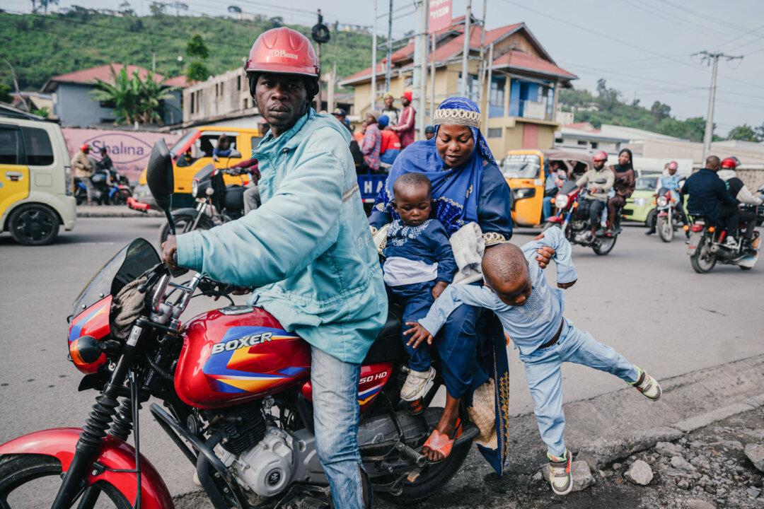 TOPSHOT - A Congolese Muslim woman helps her children get off a motorcycle taxi to attend Eid al-Fitr prayers, marking the end of the holy month of Ramadan, at Unity Stadium in Goma on March 20, 2026. (Photo by Jospin Mwisha / AFP via Getty Images)