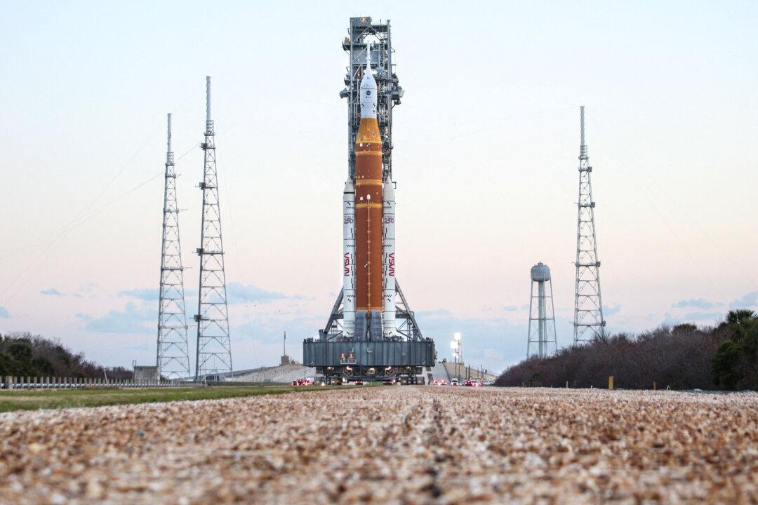 TOPSHOT - Mobile launcher 1 containing the massive Artemis II Space Launch System (SLS) rocket and Orion spacecraft rolls toward Launch Pad 39B at the Kennedy Space Center in Cape Canaveral, Florida at sunrise on March 20, 2026. NASA on March 19 began returning its towering SLS rocket and Orion spacecraft to its Florida launch pad ahead of a planned flyby of the Moon, after completing necessary repairs. Artemis engineers began the maneuver, which can take up to 12 hours, at 8:00 pm eastern, after which the US space agency will begin final preparations before its next launch window opens on April 1. (Photo by Gregg Newton / AFP via Getty Images)