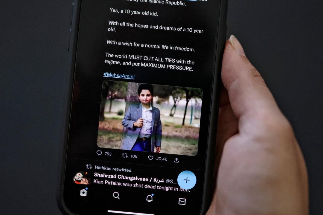 A woman looking at a social media post on her phone screen reportedly showing an Iranian boy who was killed in a shooting attack earlier this week in the western Iranian town of Izeh, in Nicosia, Cyprus, on Nov. 18, 2022. (-/AFP via Getty Images)