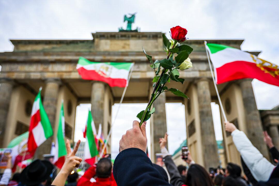 People, many of them expatriate Iranians living in Berlin, hold up flags and roses as they gather to celebrate Nowruz, the Persian new year, in Berlin on March 20, 2026. (Omer Messinger/Getty Images)