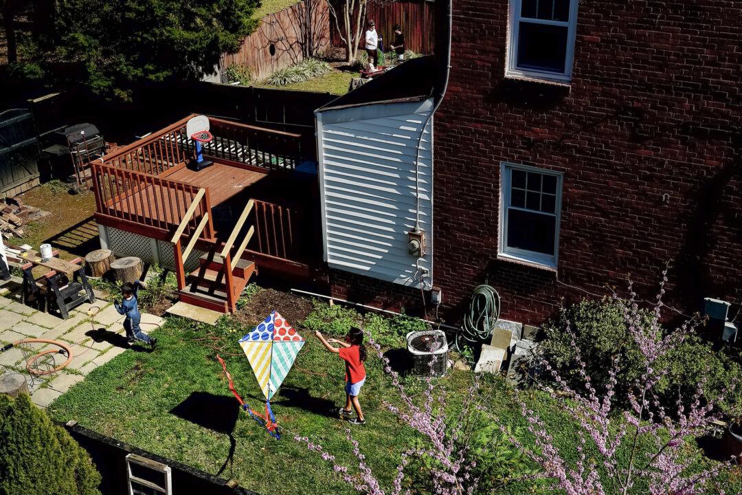 Children attempt to fly a kite in their backyard in Arlington, Va., on April 9, 2020. A Redfin report from January shows home sellers outnumber buyers by a record margin. It’s a buyer’s market for those who can afford it. (Olivier Douliery/AFP via Getty Images)