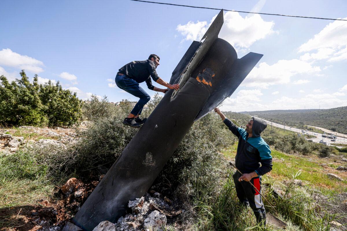 A Palestinian man climbs on the remnants of an Iranian missile that landed in the Israeli-occupied West Bank village of Hares on March 24, 2026. (Jaafar Ashtiyeh/AFP via Getty Images)