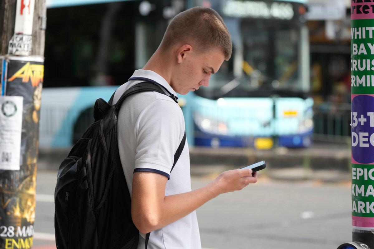 A teenager is pictured using his cellphone as he waits to cross the street in Sydney on Dec. 8, 2025. (AP Photo/Rick Rycroft)