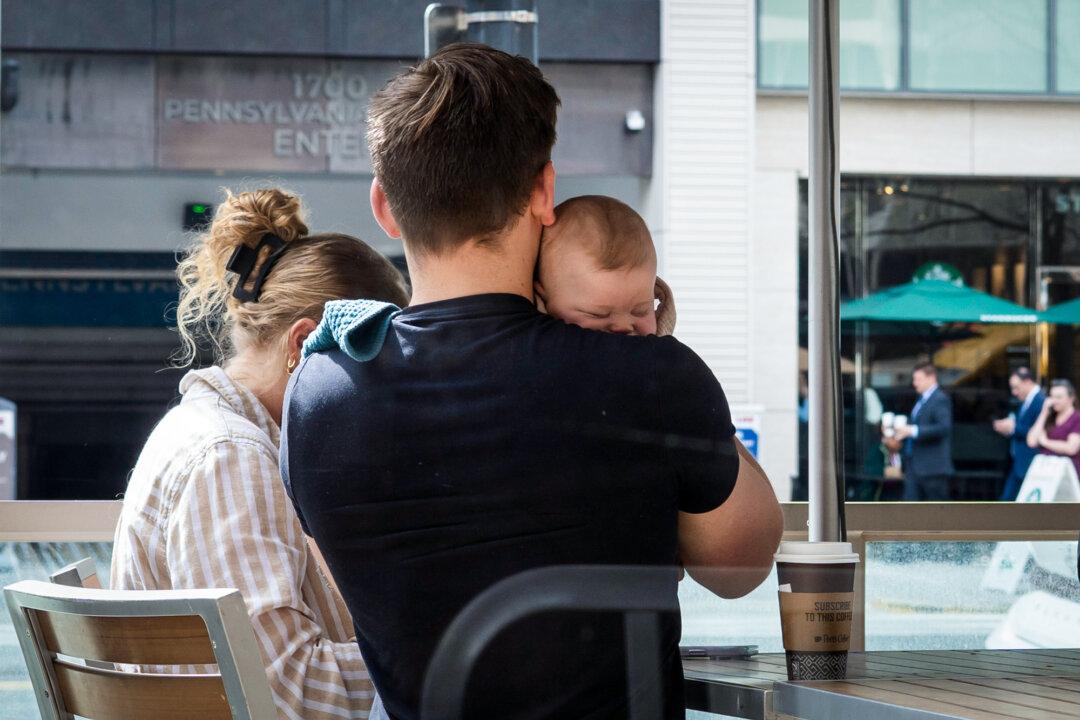 A man holds a baby outside a coffee shop in Washington on March 11, 2026. Supreme Court justices are expected to weigh the meaning of the 14th Amendment’s citizenship clause, including whether birth within U.S. borders alone is sufficient for citizenship. (Madalina Kilroy/The Epoch Times)