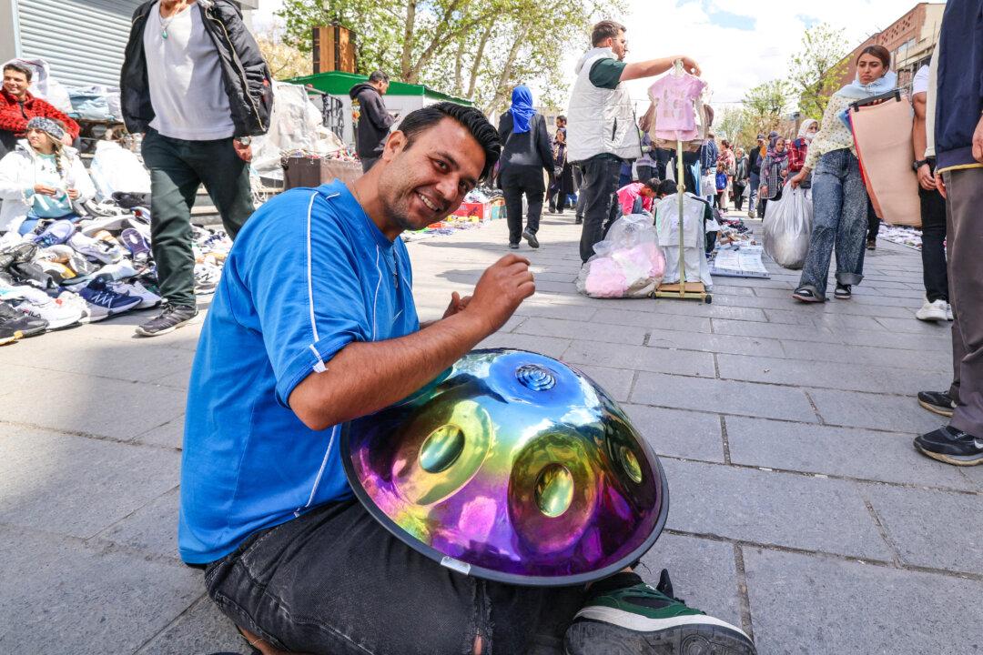 A man plays music as people walk at the Grand Bazaar in Tehran, Iran, on March 30, 2026. (Atta Kenare / AFP via Getty Images) /
