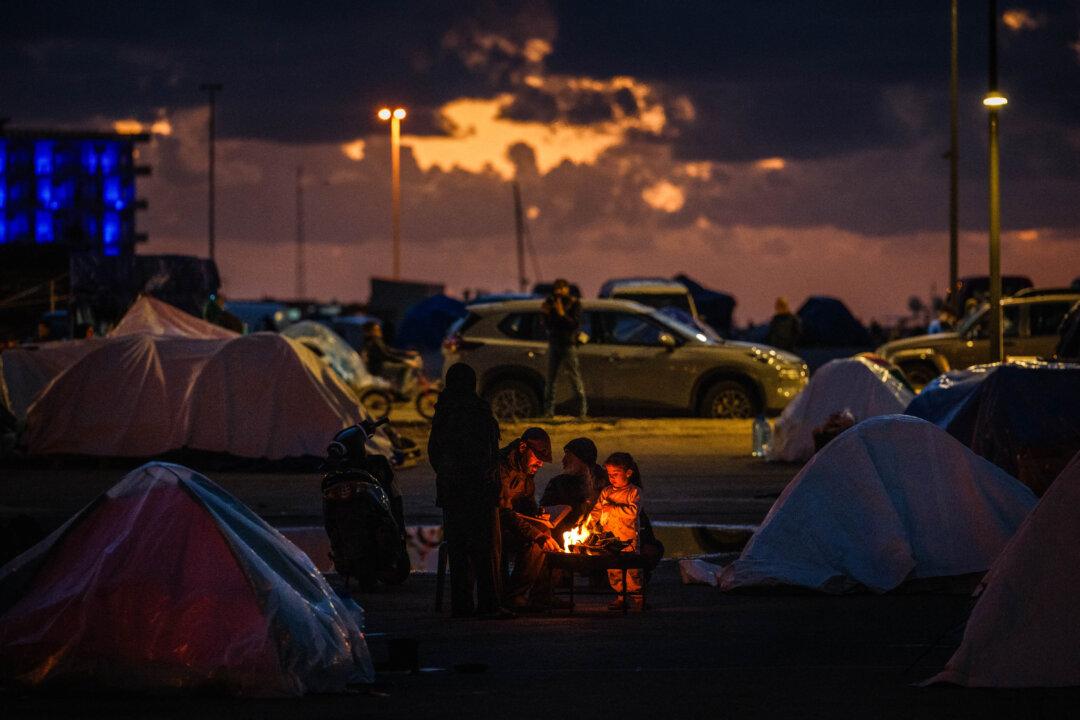 Displaced people warm up around a fire outside their tent along Beirut’s seafront area in Lebanon on March 30, 2026. (Dimitar Dilkoff / AFP via Getty Images)