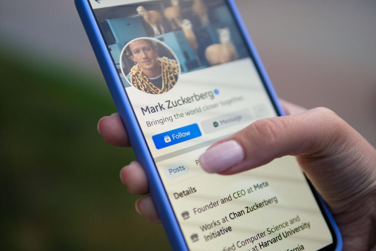 A woman holds a phone displaying the Facebook app, in this file photo taken on Aug. 11, 2024. (Oleksii Pydsosonnii/The Epoch Times)