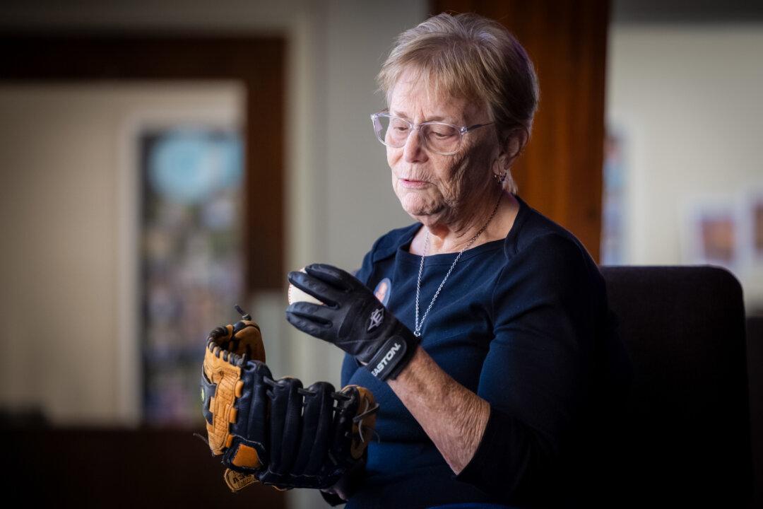 Judy Rogg holds a baseball and glove used by her late son Erik in Los Angeles on April 15, 2026. (John Fredricks/The Epoch Times)