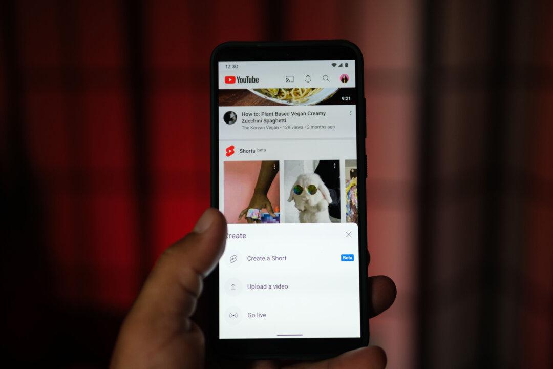 A man holds a phone displaying the YouTube app in this file photo. Algorithms and viral sharing on platforms such as YouTube and TikTok have amplified the reach of the “choking game” challenge, turning a once localized dare into a global trend. (Oleksii Pydsosonnii/The Epoch Times)