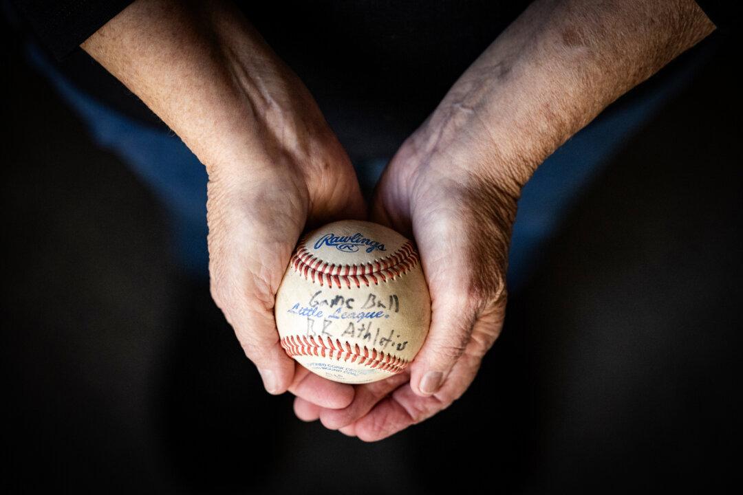 (Left) Judy Rogg holds one of the baseballs used and written on by her deceased son Erik in Los Angeles on April 15, 2026. (Right) A photo of Erik Robinson sits next to items he owned in Los Angeles on April 15, 2026. (John Fredricks/The Epoch Times)