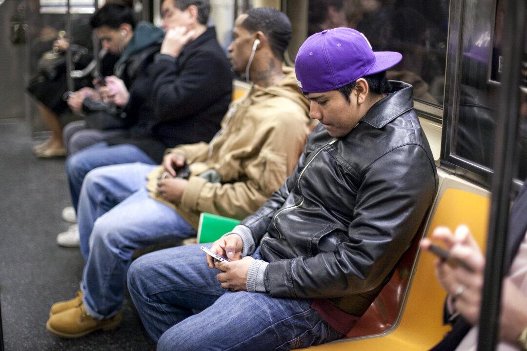 People look at their phones on the subway in New York on April 1, 2014. (Samira Bouaou/The Epoch Times)