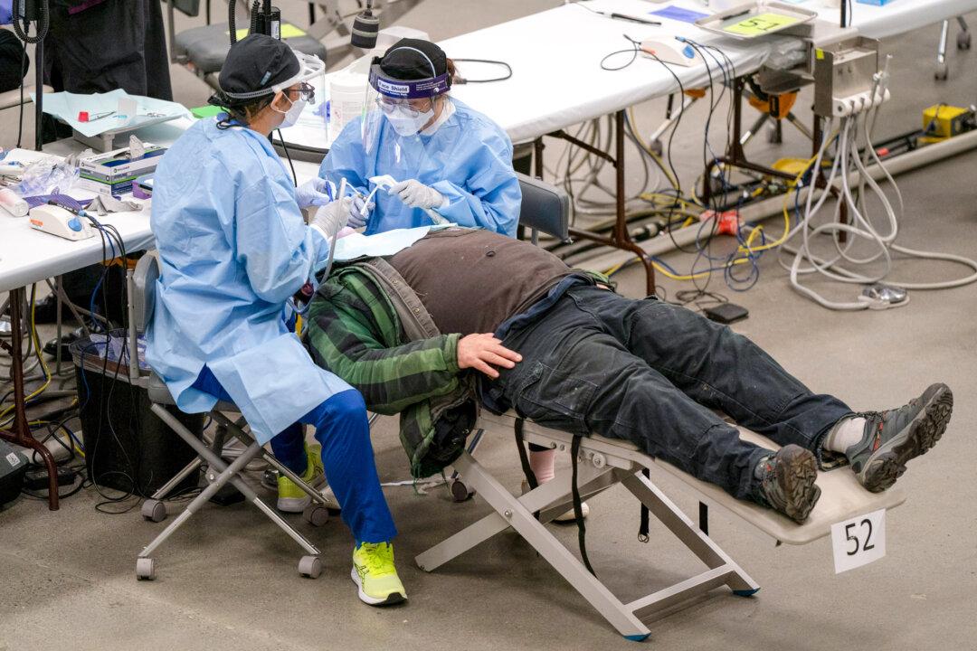 Around 8 percent of Americans do not have health insurance. Volunteers offer free dental work for a patient during a health care event in Seattle on Feb. 16, 2024. (David Ryder/Getty Images)