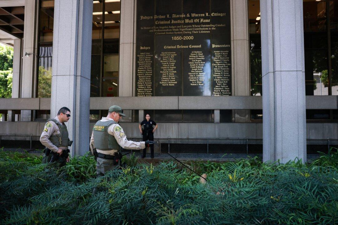 A Los Angeles County sheriff and his dog search for a suspected bomb outside Los Angeles County Superior Court ahead of US singer D4vd's arraignment in Los Angeles on April 20, 2026. Rising star D4vd, whose real name is David Burke, was arrested in connection to the murder of a teenage girl whose dismembered body was found in the trunk of a car registered in the artist's name, police said on April 16. (Photo by Patrick T. Fallon / AFP via Getty Images)