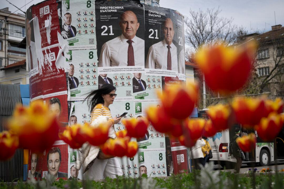 A woman walks past election posters of the Progressive Bulgaria coalition's leader and former President Rumen Radev in Sofia on April 20, 2026. Bulgaria held its eighth legislative election in five years, with ex-president Rumen Radev's grouping tipped to win on a pledge to fight corruption, after an anti-graft movement triggered a long political crisis. (Photo by Nikolay DOYCHINOV / AFP via Getty Images)