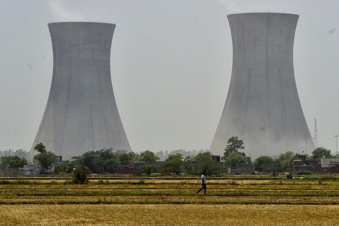 NEW DELHI, INDIA - APRIL 21: A man passes through a thermal power plant with cooling towers are seen in an industrial area on April 21, 2026 in the outskirts of New Delhi, India. India, which imports roughly 88 percent of its crude oil and had been steadily expanding purchases of discounted Iranian barrels before the conflict escalated, now faces mounting pressure to secure alternative supplies as tanker insurance costs and shipping routes through the Persian Gulf come under renewed strain. (Photo by Ritesh Shukla/Getty Images)