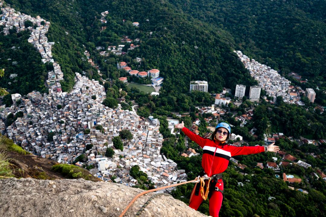 A tourist abseils at sunrise from Morro Dois Irmaos, reached via the Vidigal favela, a day after a police operation in Rio de Janeiro, Brazil, on April 21, 2026. A police operation against drug trafficking took place in the Vidigal favela early morning on April 20, in the touristy south zone of Rio de Janeiro, during which around 200 tourists were temporarily stranded on Morro Dois Irmaos, from where they were later evacuated unharmed by local tour guides. (Photo by Pablo PORCIUNCULA / AFP via Getty Images)