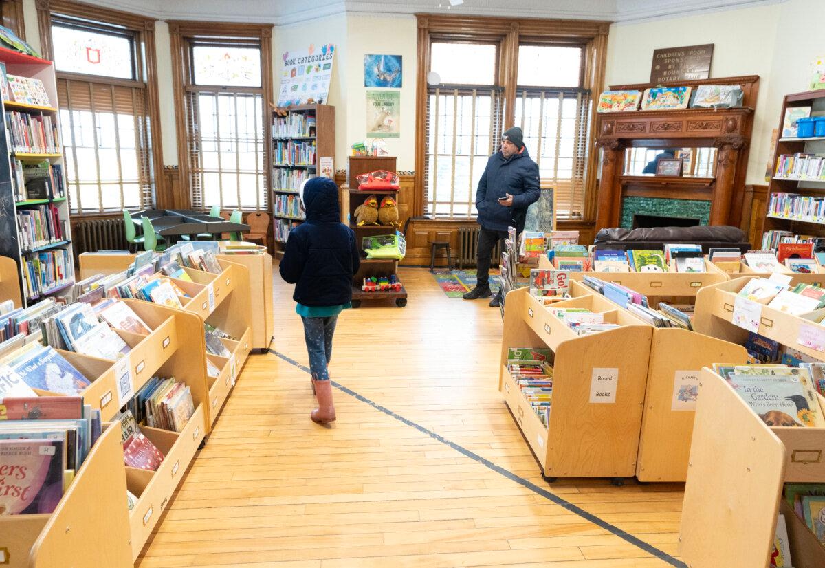A young girl walks over the Canada-USA international border line into Canada from inside the Haskell Free Library and Opera House in Derby Line, Vermont, on March 21, 2025. (The Canadian Press/Christinne Muschi)