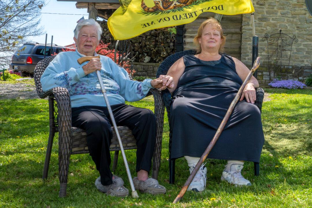 Ida Huddleston, 82 (L), and her daughter Delsia Bare, 54, sit by their “Don’t Tread On Me” flag in the yard of their family farm in Maysville, Ky., on April 10, 2026. (Glenn Hartong for The Epoch Times)