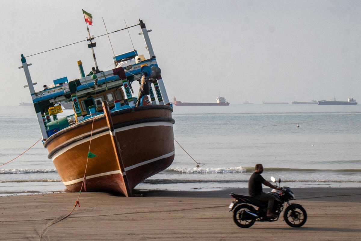 An Iranian man rides a motorcycle past a boat at Suru Beach in Bandar Abbas, Iran, on April 24, 2026. (Razieh Poudat/ISNA/AFP via Getty Images)