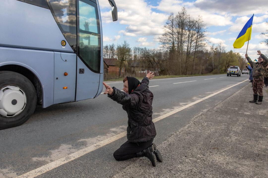 TOPSHOT - A woman kneels on a road as she greets released Ukrainian prisoners of war (POWs) passing by in buses following a prisoner exchange, in the Chernihiv region on April 24, 2026, amid the Russian invasion of Ukraine. Russia and Ukrain swapped 193 captured soldiers each, the second exchange this month in one of the few areas of cooperation between Moscow and Kyiv. The two countries have exchanged thousands of POWs throughout the four-year war -- with the swaps often the only result of otherwise stalled talks on ending the conflict. (Photo by Roman PILIPEY / AFP via Getty Images)