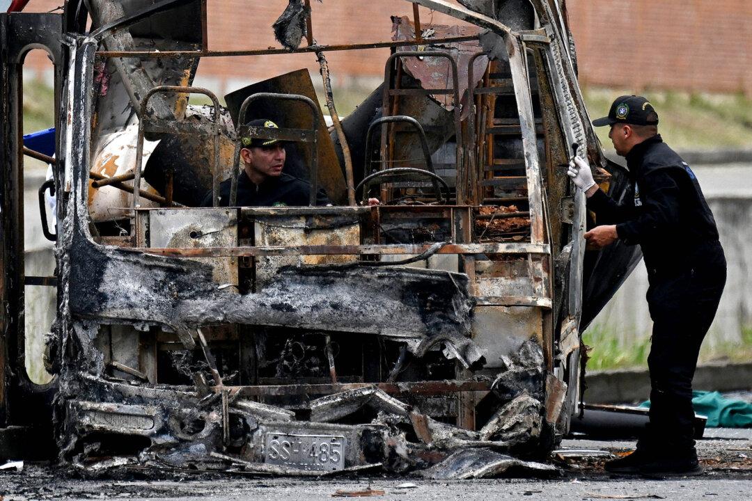 Colombian bomb disposal officers inspect a bus burned after a bomb explosion near a military base in Cali, Valle del Cauca department, Colombia on April 24, 2026. One person was injured in an attack on a military base in southwest Colombia, according to the local health authority on April 24, 2026, one month ahead of the presidential election. (Photo by JOAQUIN SARMIENTO / AFP via Getty Images)
