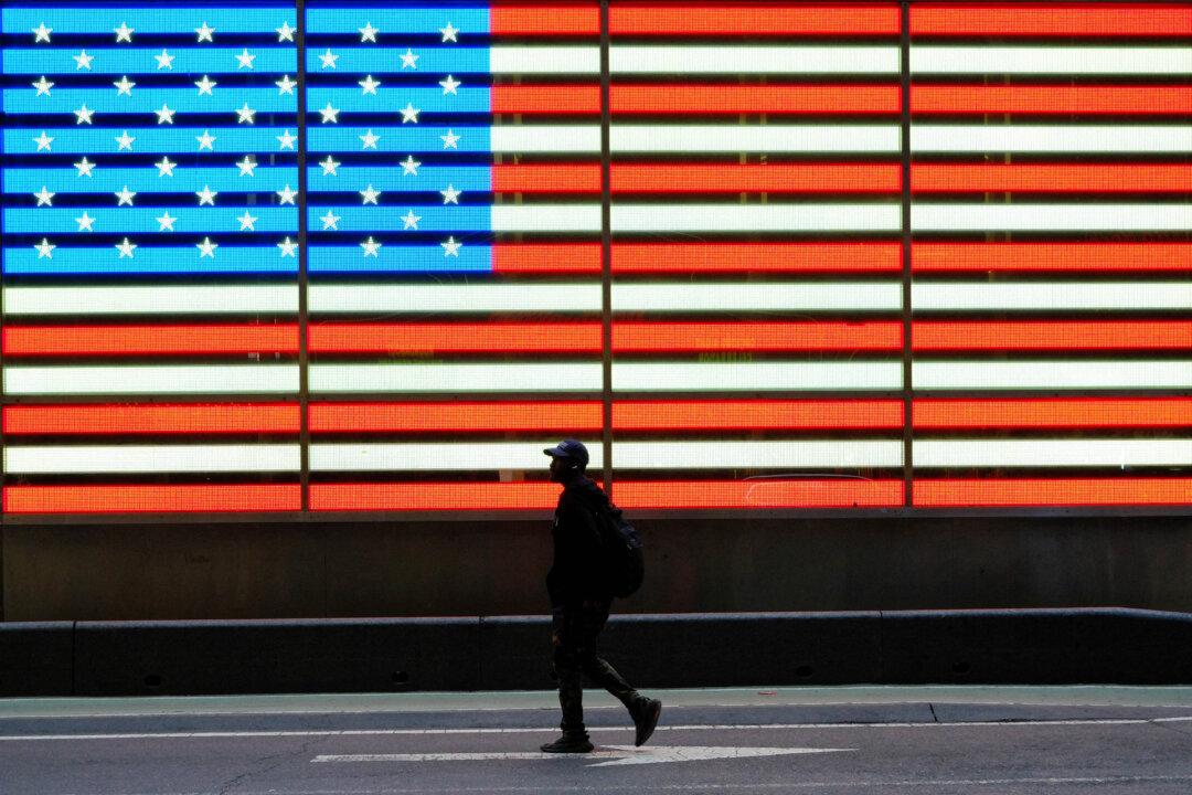 A man walks past a giant US flag in Times Square in the Manhattan borough of New York City on April 24, 2026. (Photo by CHARLY TRIBALLEAU / AFP via Getty Images)