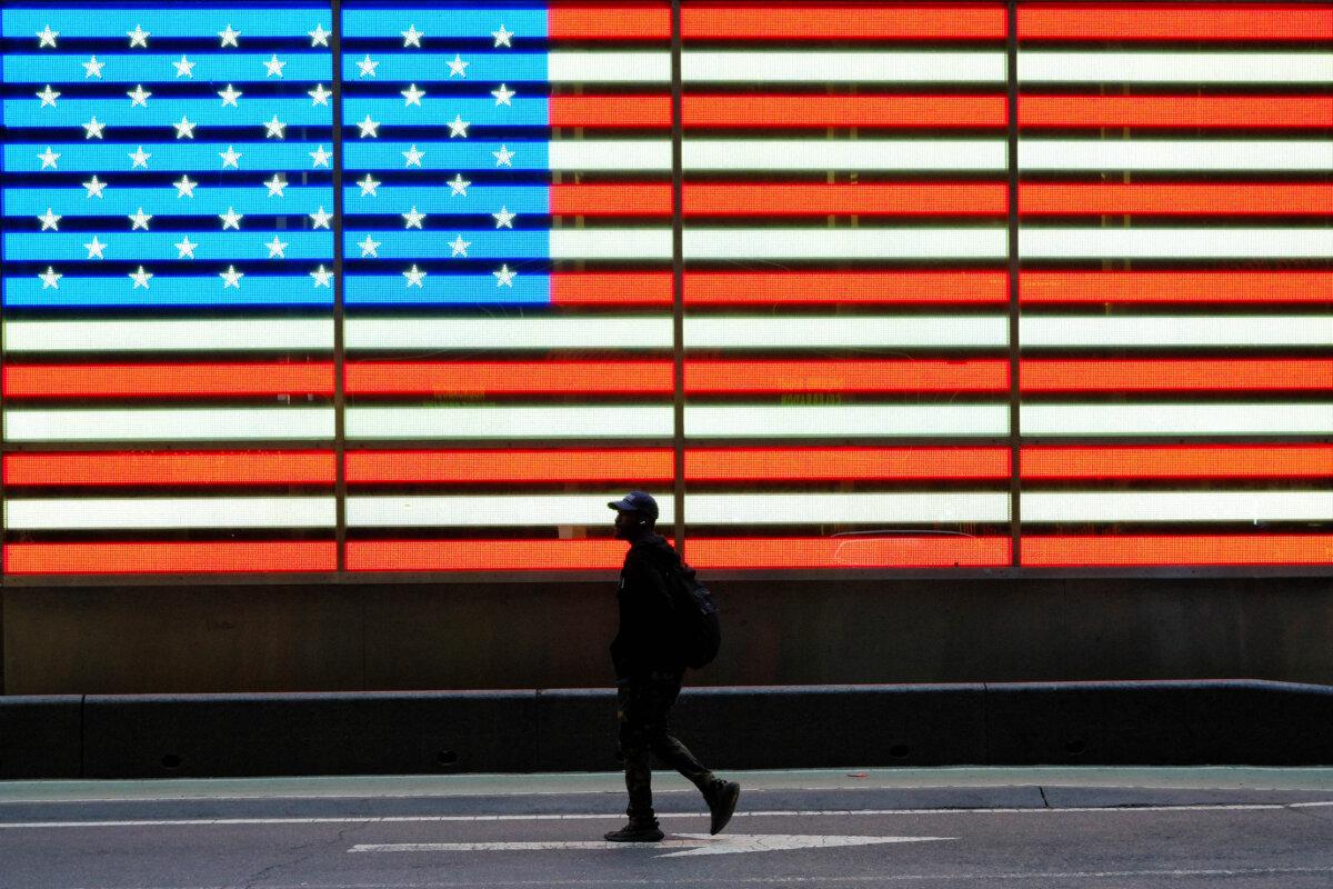 A man walks past a large U.S. flag in Times Square in Manhattan, New York City, on April 24, 2026. (Charly Triballeau/AFP via Getty Images)