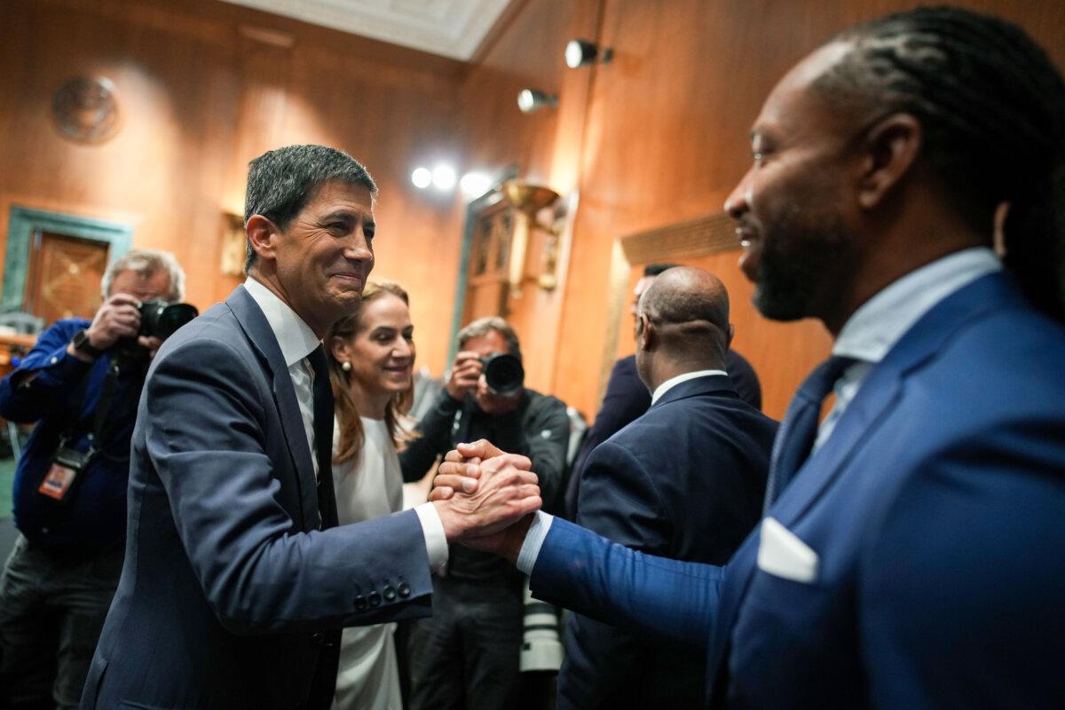 Kevin Warsh (L), U.S. President Donald Trump's nominee for Chair of the Federal Reserve, greets former NFL player Larry Fitzgerald Jr. (R) during his Senate Committee on Banking, Housing, and Urban Affairs confirmation hearing in the Dirksen Senate Office Building in Washington on April 21, 2026. (Andrew Harnik/Getty Images)
