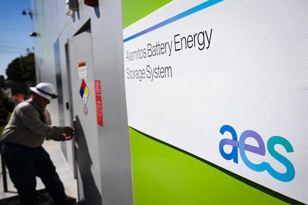 The AES logo is displayed outside a building containing the AES Alamitos Battery Energy Storage System, which provides stored renewable energy to supply electricity during peak demand periods, in Long Beach, Calif., on Sept. 16, 2022. (Patrick T. Fallon/AFP via Getty Images)