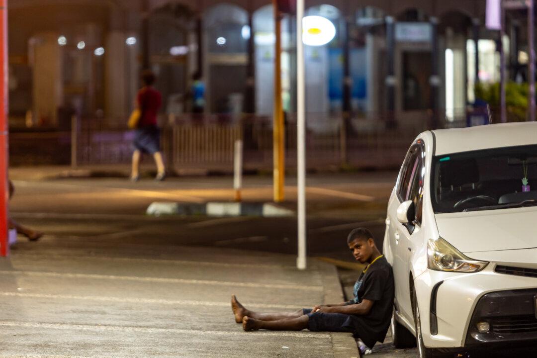 A young man sits on the edge of a pavement on the streets of Suva City, Fiji, on April 29, 2026. (Pita Simpson/Getty Images)