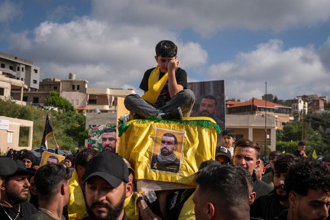 The son of a slain Hezbollah fighter sits on his father's coffin as it is carried during a funeral ceremony in Sammaaiyeh, Lebanon on April 29, 2026. (Adri Salido/Getty Images)
