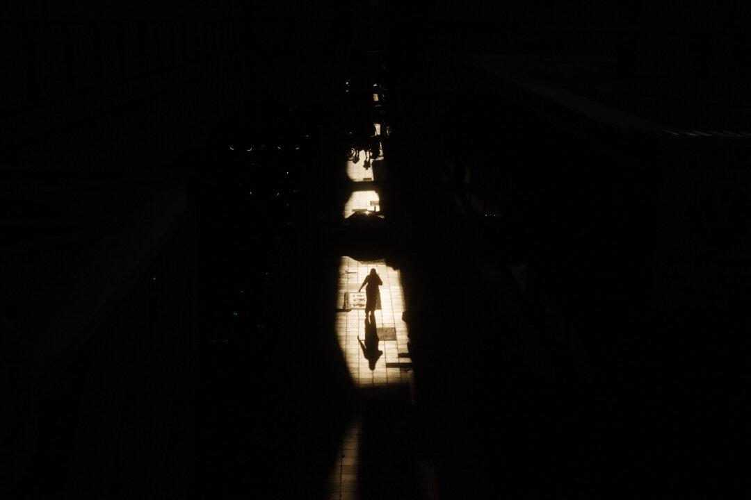 A pedestrian is silhouetted by the sun shining through gaps on a pavement in Bangkok, on April 29, 2026. (Anthony Wallace/ AFP via Getty Images)