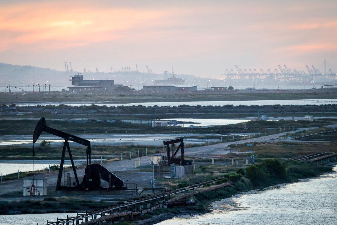 A pumpjack stands idle in the Huntington Beach oil field, with port cranes visible in the distance, in Huntington Beach, Calif., on April 23, 2026. America benefits not only from domestic supply but also from substantial imports from Canada. (Mario Tama/Getty Images)