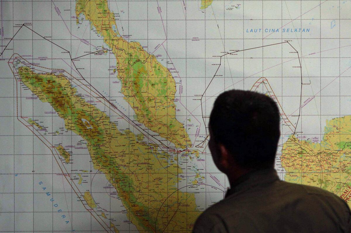 A member of the Indonesian Air Force at Medan city military base inspects a map of the Malacca Strait, a sea passageway between Indonesia (seen left of the map) and Malaysia (seen top left of the map), on March 12, 2014. (ATAR / AFP via Getty Images)