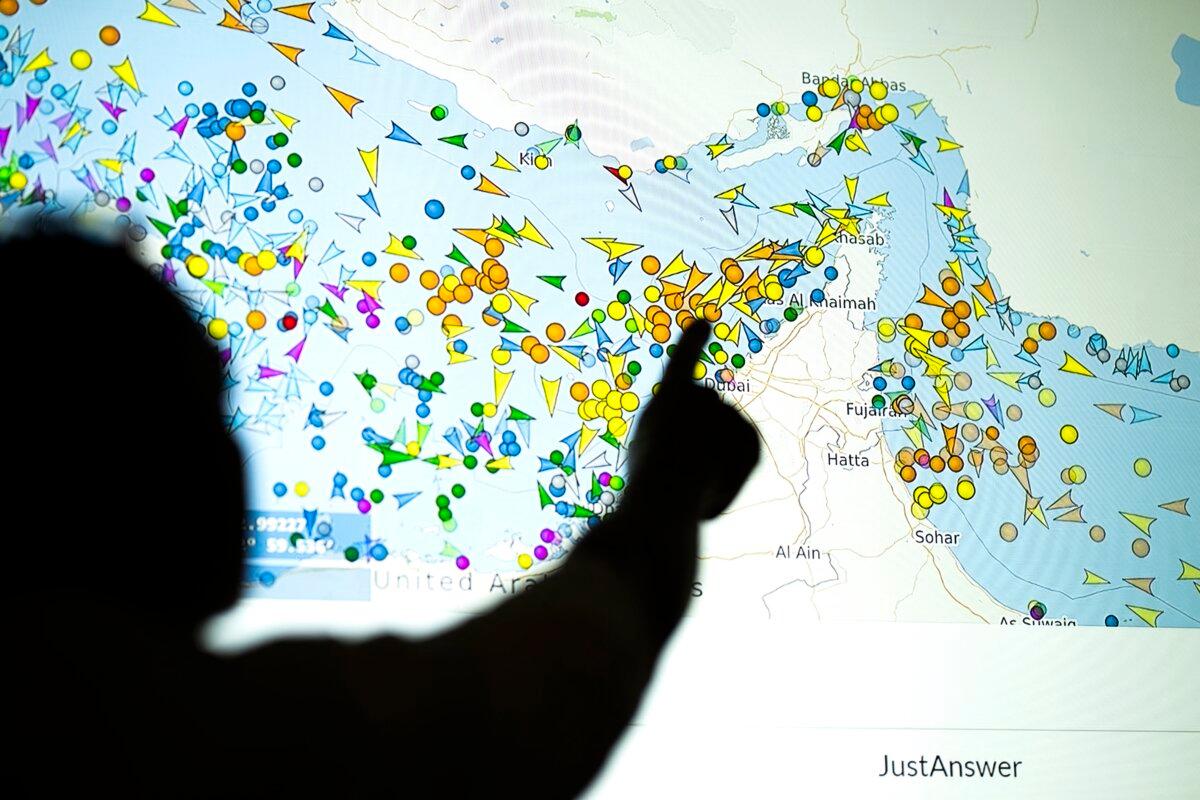 A photo illustration shows a person in front of a large screen displaying vessel movements in the Strait of Hormuz on a ship-tracking website, in Nicosia, Cyprus, on May 4, 2026. (AFP)