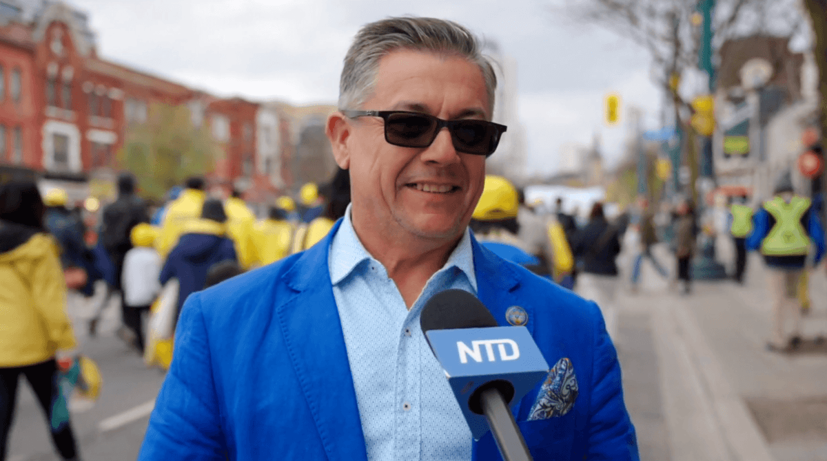 Joe DaSilva, a Portuguese bakery owner in Toronto, speaks to NTD as he watches the World Falun Dafa Day parade in downtown Toronto on May 3, 2026. (NTD)