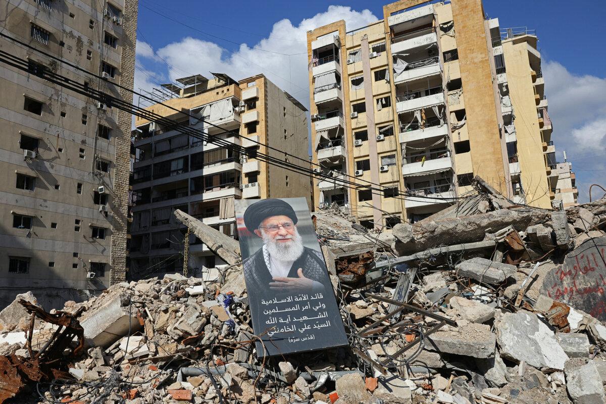 This photograph, taken during a media tour organized by Hezbollah's media office, shows a banner with a picture of late Iranian supreme leader Ayatollah Ali Khamenei, placed amid the rubble of a destroyed building near Sayyid al-Shuhada complex in the southern suburbs of Beirut, Lebanon, on May 6, 2026. (Anwar Amro/ AFP via Getty Images)