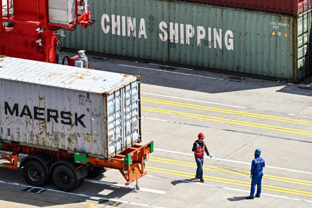 Workers stand next to a truck transporting a container at the Yangshan Deep-Water Port near Shanghai on June 3, 2025. (Hector Retamal/AFP via Getty Images)
